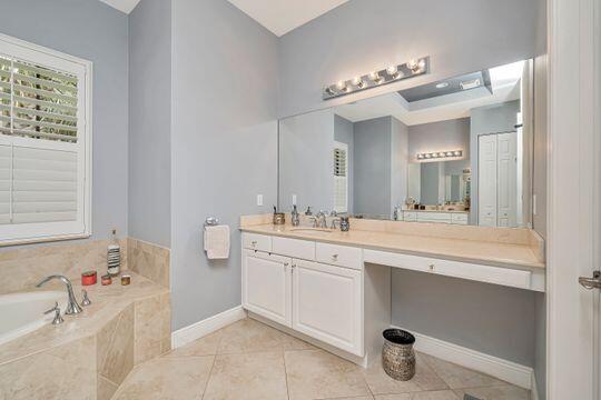 bathroom with vanity, tile patterned floors, and a relaxing tiled tub