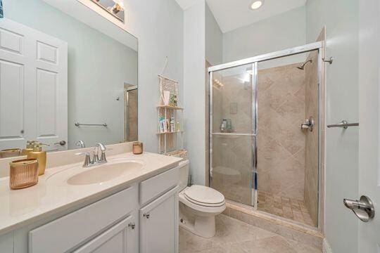 bathroom with tile patterned floors, an enclosed shower, vanity, and toilet