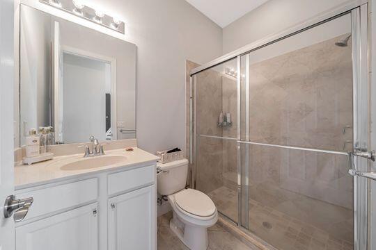 bathroom with vanity, toilet, and a shower with door