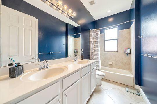 full bathroom featuring shower / bath combo with shower curtain, tile patterned flooring, vanity, and toilet