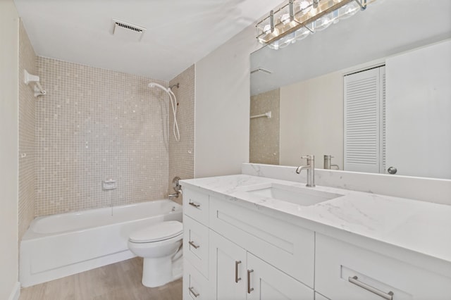 full bathroom featuring wood-type flooring, toilet, tiled shower / bath combo, and vanity