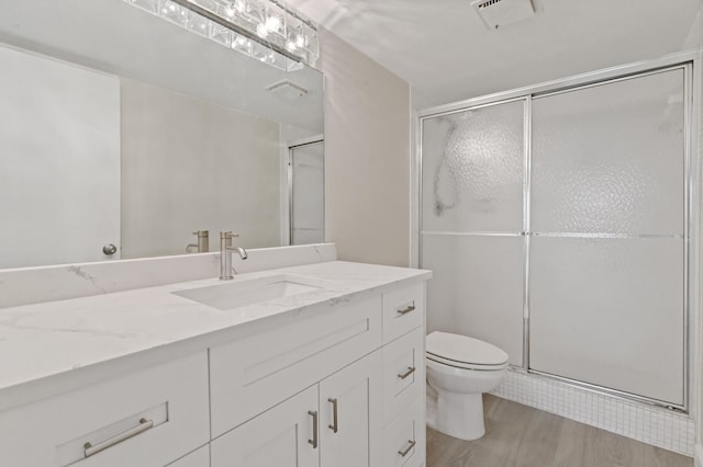 bathroom featuring a shower with door, vanity, hardwood / wood-style flooring, and toilet