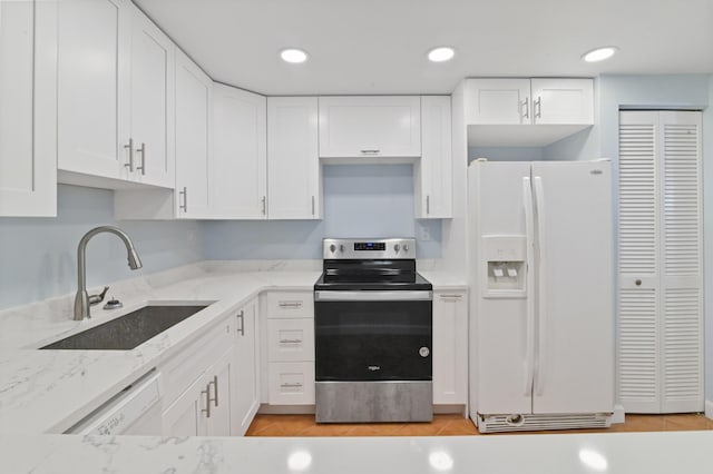 kitchen with white cabinets, white appliances, sink, light stone countertops, and light hardwood / wood-style flooring