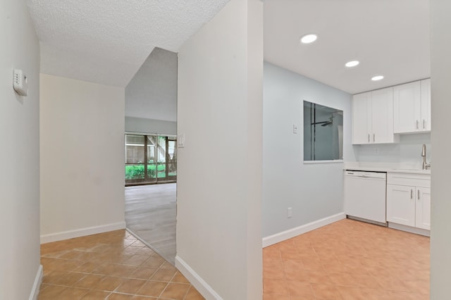 kitchen with white cabinetry, white dishwasher, a textured ceiling, and light tile patterned floors