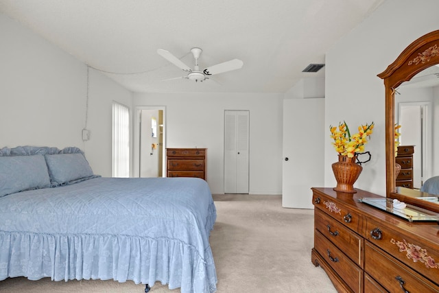 bedroom with light carpet, a closet, ceiling fan, and ensuite bathroom