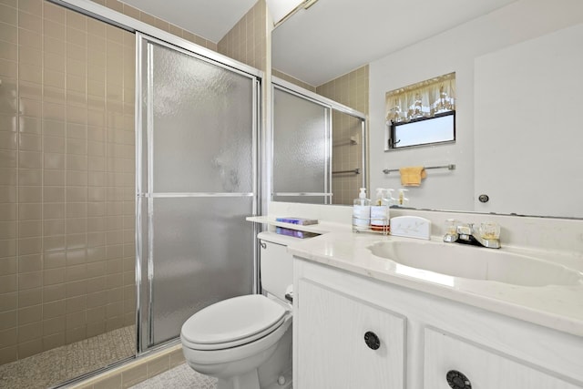 bathroom featuring a shower with shower door, vanity, and toilet