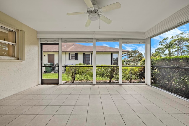 unfurnished sunroom featuring ceiling fan and a wealth of natural light