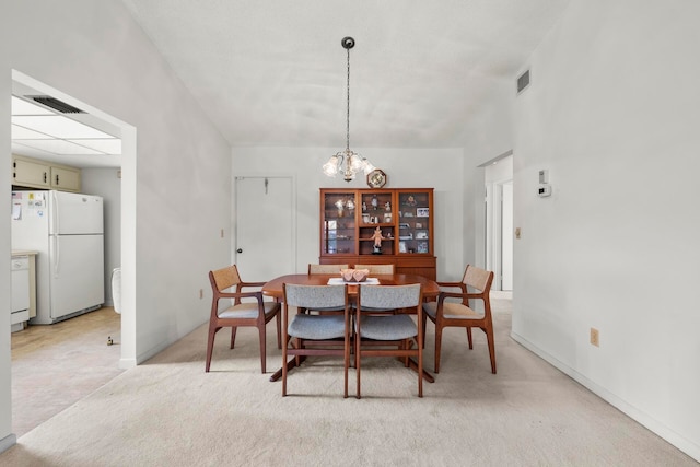 dining room with light colored carpet and an inviting chandelier