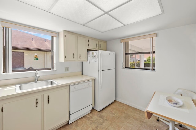 kitchen with light tile patterned floors, white appliances, sink, and cream cabinetry