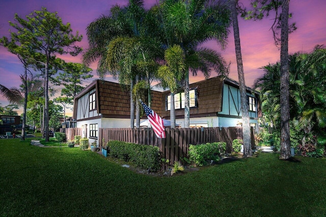 back house at dusk featuring a lawn