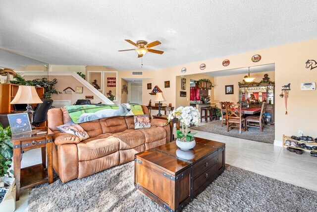 living room with a textured ceiling, light tile patterned floors, and ceiling fan