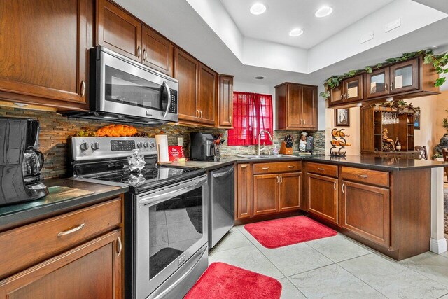 kitchen featuring light tile patterned flooring, kitchen peninsula, stainless steel appliances, decorative backsplash, and sink