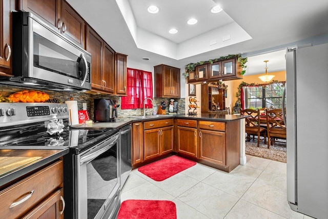 kitchen featuring tasteful backsplash, stainless steel appliances, sink, light tile patterned flooring, and a raised ceiling