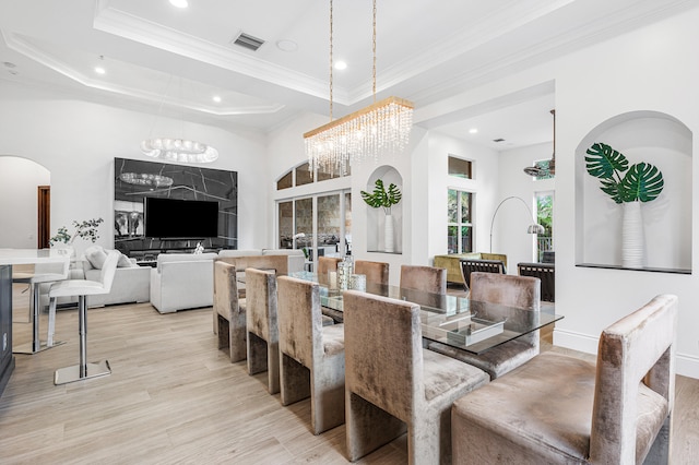 dining area featuring a notable chandelier, light hardwood / wood-style flooring, a raised ceiling, and ornamental molding