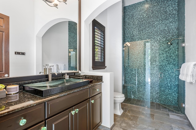 bathroom featuring a shower with shower door, vanity, tile patterned floors, and toilet