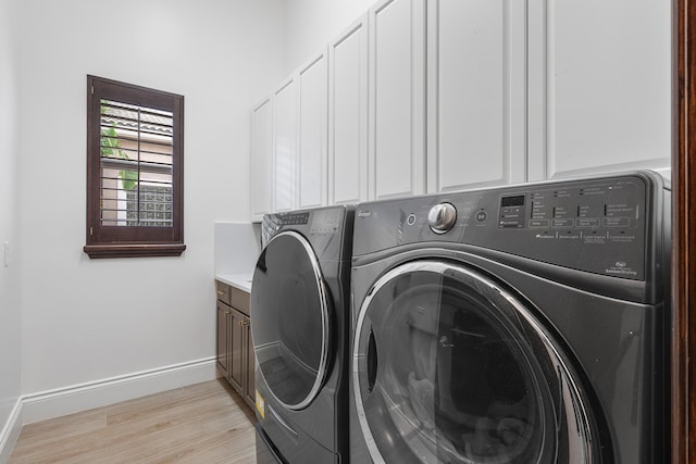 washroom featuring light wood-type flooring, separate washer and dryer, and cabinets