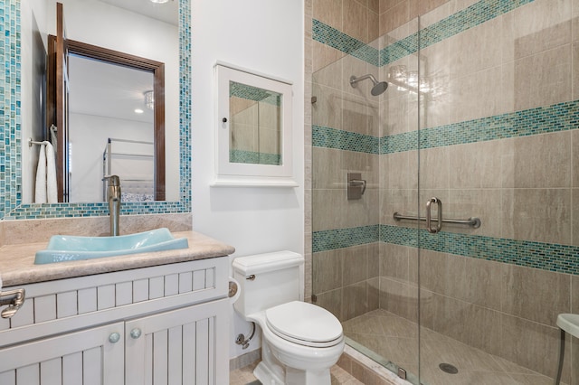 bathroom with tile walls, toilet, vanity, and an enclosed shower