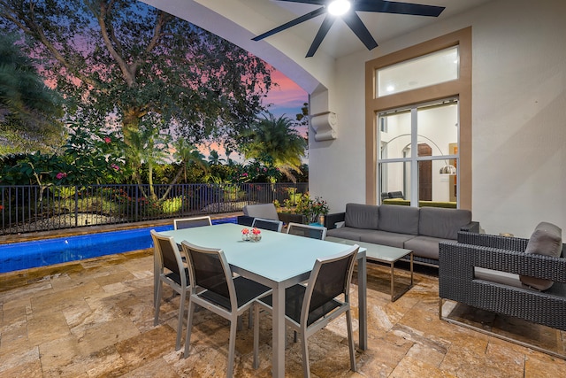 patio terrace at dusk with ceiling fan, a fenced in pool, and an outdoor living space