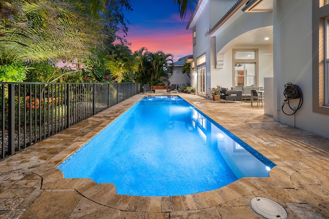 pool at dusk featuring a patio area