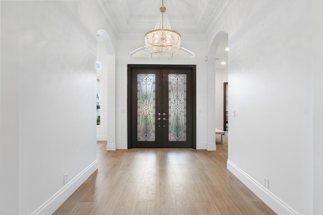 foyer with a notable chandelier, light wood-type flooring, and french doors