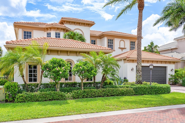 mediterranean / spanish house featuring a garage and a front yard