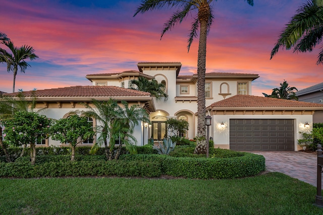 mediterranean / spanish-style home with a lawn and a garage