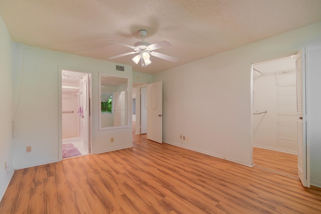 unfurnished bedroom with light hardwood / wood-style floors, a walk in closet, and ensuite bath