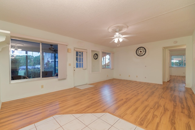 empty room with a textured ceiling, light hardwood / wood-style flooring, and ceiling fan