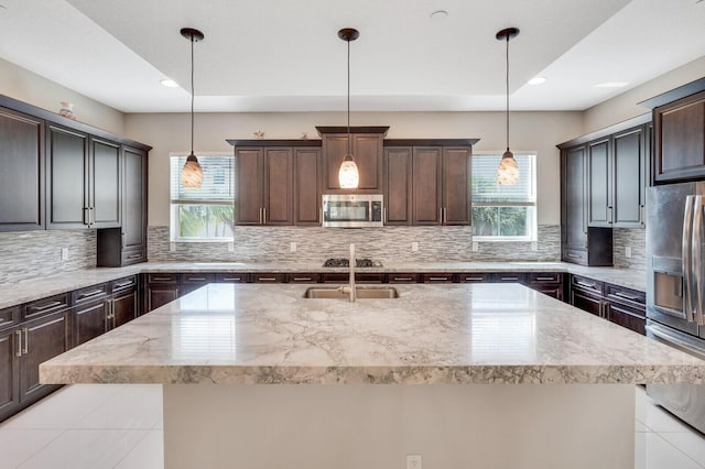 kitchen with a kitchen island with sink, pendant lighting, and stainless steel appliances