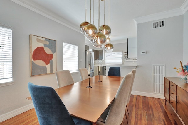 dining area featuring light hardwood / wood-style flooring, ornamental molding, and a chandelier