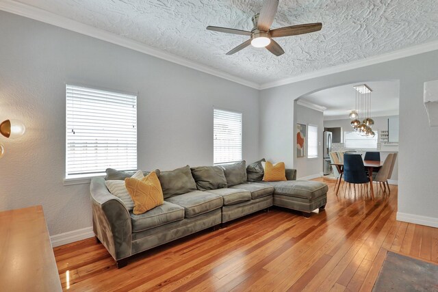 living room featuring ceiling fan with notable chandelier, a textured ceiling, crown molding, and hardwood / wood-style flooring