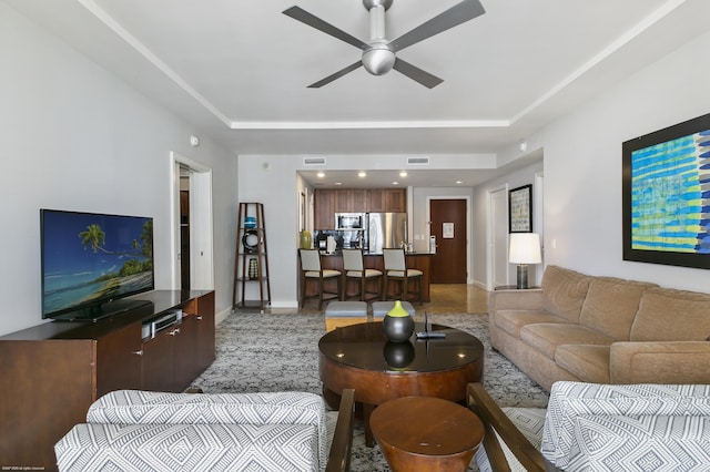 living room with a raised ceiling and ceiling fan