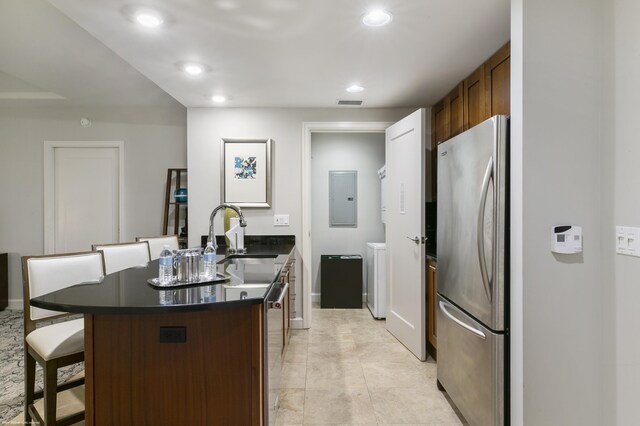 kitchen featuring a kitchen island, sink, stainless steel fridge, a kitchen bar, and electric panel