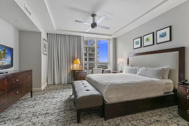 bedroom featuring light colored carpet, a raised ceiling, and ceiling fan