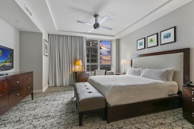 carpeted bedroom featuring ceiling fan and a raised ceiling