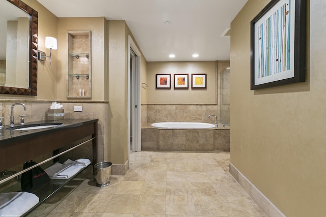 bathroom featuring tiled tub, vanity, tasteful backsplash, and tile patterned flooring