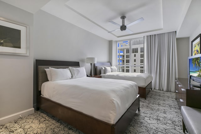 bedroom with multiple windows, a tray ceiling, and ceiling fan