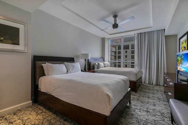 bedroom with ceiling fan and a raised ceiling