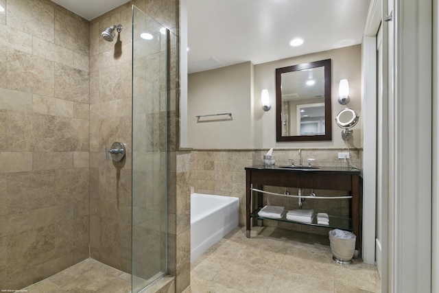 bathroom with vanity, shower with separate bathtub, and tile walls