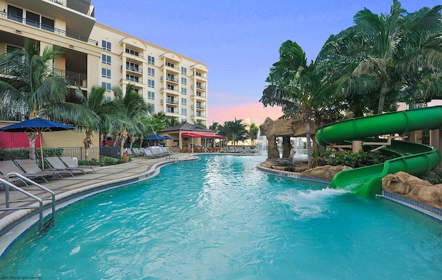 pool at dusk with a water slide and a patio area