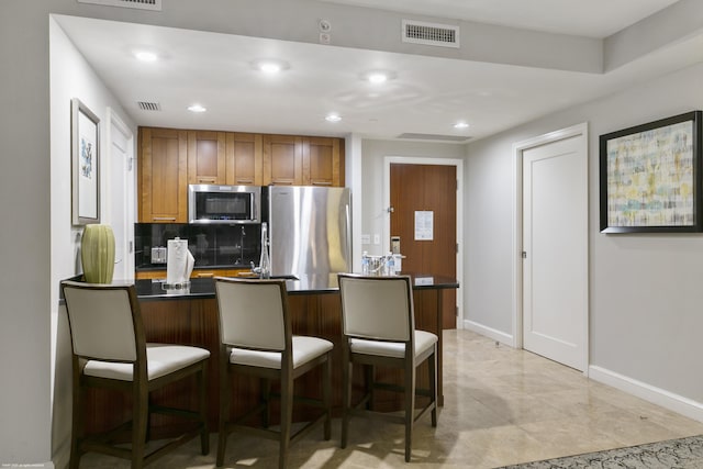 kitchen with backsplash, sink, stainless steel appliances, and a kitchen breakfast bar