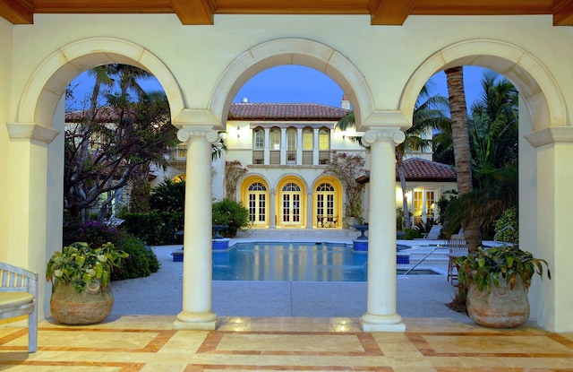 pool at dusk featuring a patio and french doors