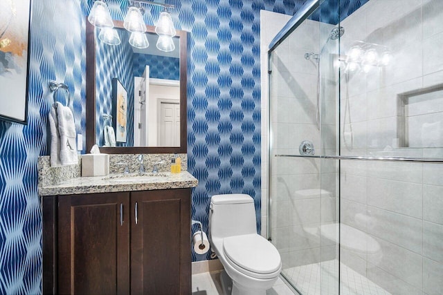 bathroom featuring a shower with shower door, vanity, and toilet