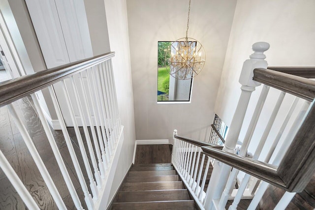 staircase featuring a high ceiling, dark hardwood / wood-style floors, and a notable chandelier