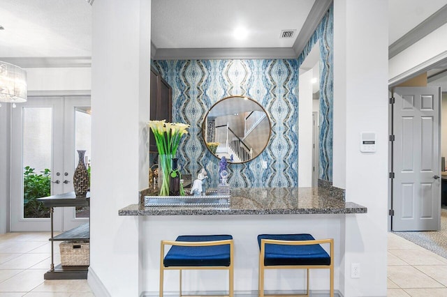 kitchen with a breakfast bar, dark stone counters, light tile patterned flooring, and kitchen peninsula