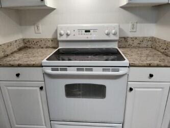 kitchen featuring white electric range oven and white cabinetry