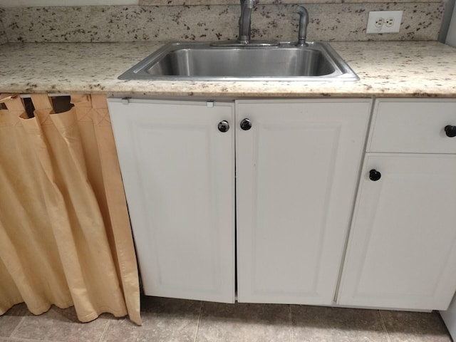 room details featuring sink, tile patterned floors, and white cabinetry