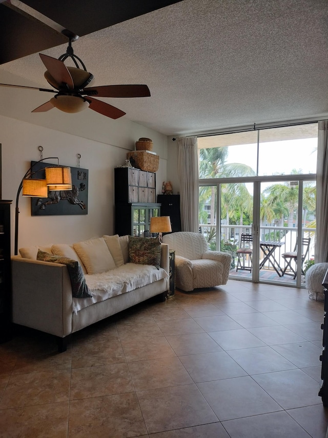 tiled living room featuring ceiling fan, expansive windows, and a textured ceiling