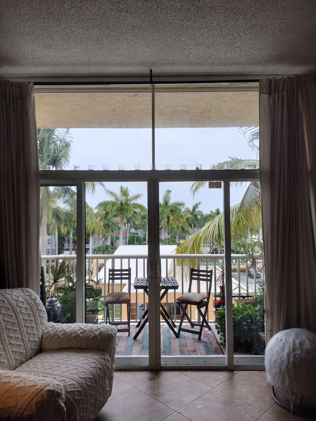 doorway to outside with a textured ceiling, a healthy amount of sunlight, and tile patterned flooring