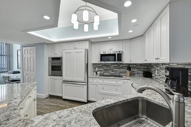 kitchen featuring sink, appliances with stainless steel finishes, white cabinetry, light stone countertops, and decorative backsplash